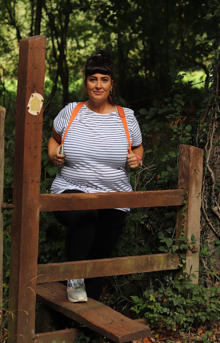 Walking is the best exercise for women over 50 woman in white and black striped shirt and black pants standing on brown wooden bridge